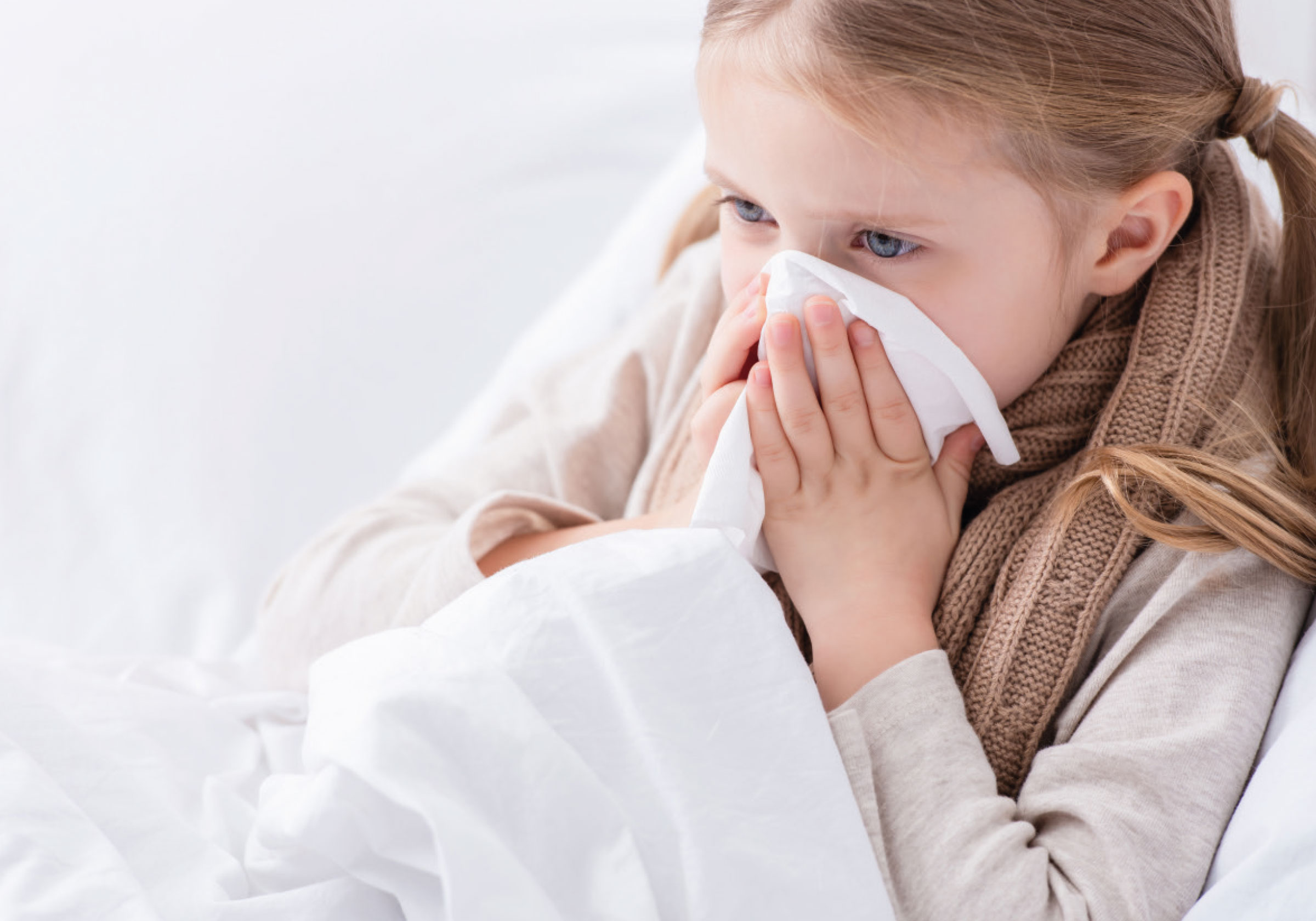 Ein Kind putzt sich die Nase mit einem Taschentuch.